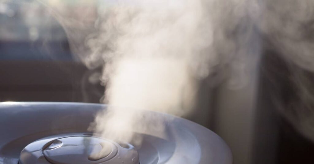A close-up of the top surface of a circular shaped humidifier as it emits steam into the surrounding air.