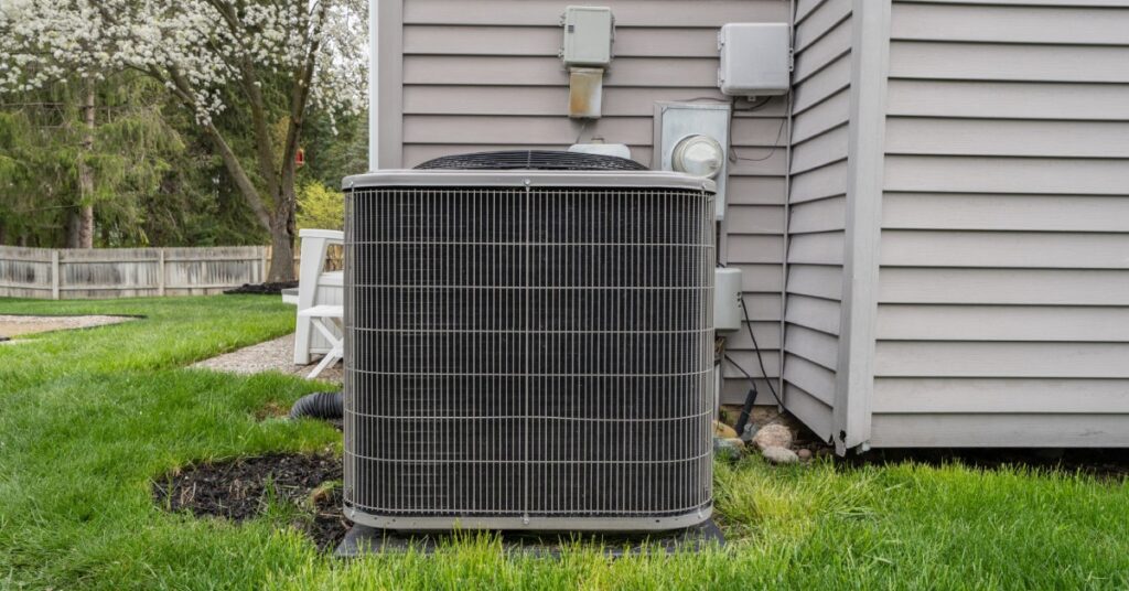 A residential air conditioning unit that is installed outside alongside a home with light gray siding.